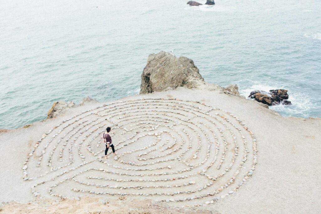 Woman working her way through a stone maze on beach